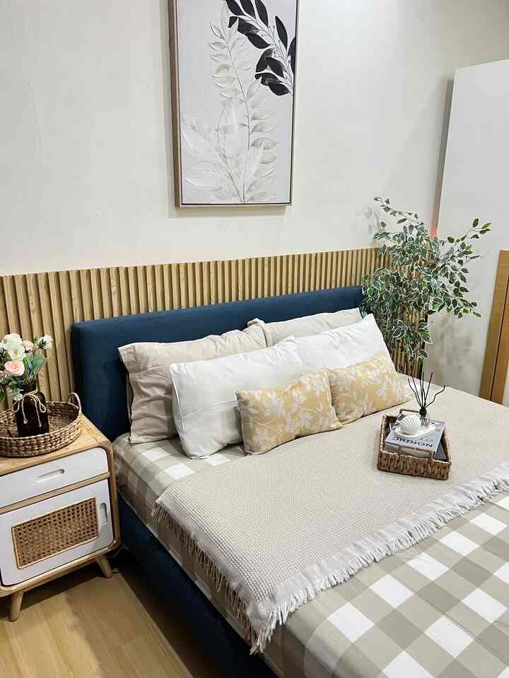 Beige and blue-tone bedroom featuring a blue bed frame, pillows, and a cozy blanket with natural decorative elements