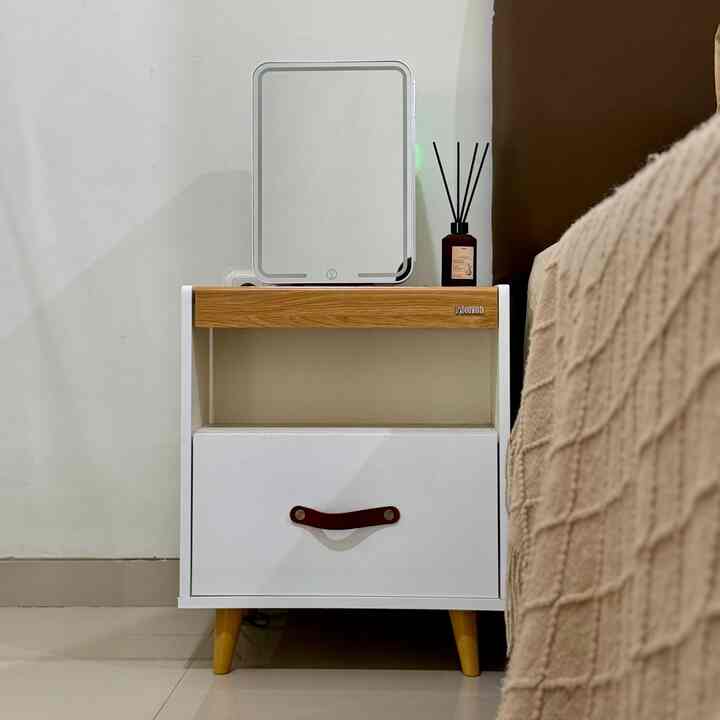 Cozy bedroom corner with a white and brown nightstand featuring yellow legs and a diffuser beside the bed