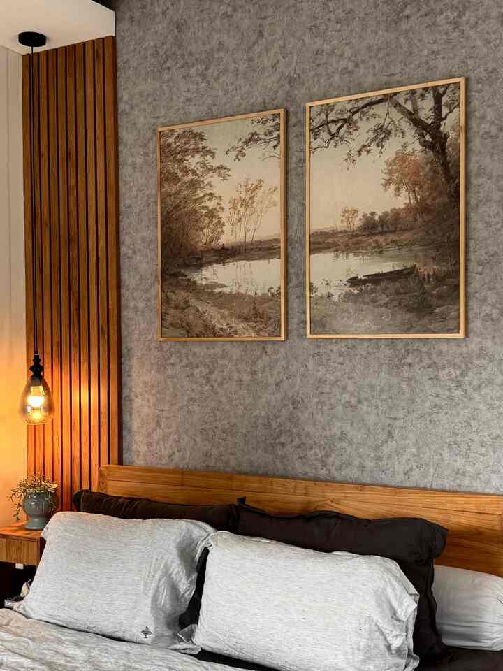 Gray textured wall and brown wooden furniture bedroom featuring two nature landscape picture frames above the bed, cozy atmosphere