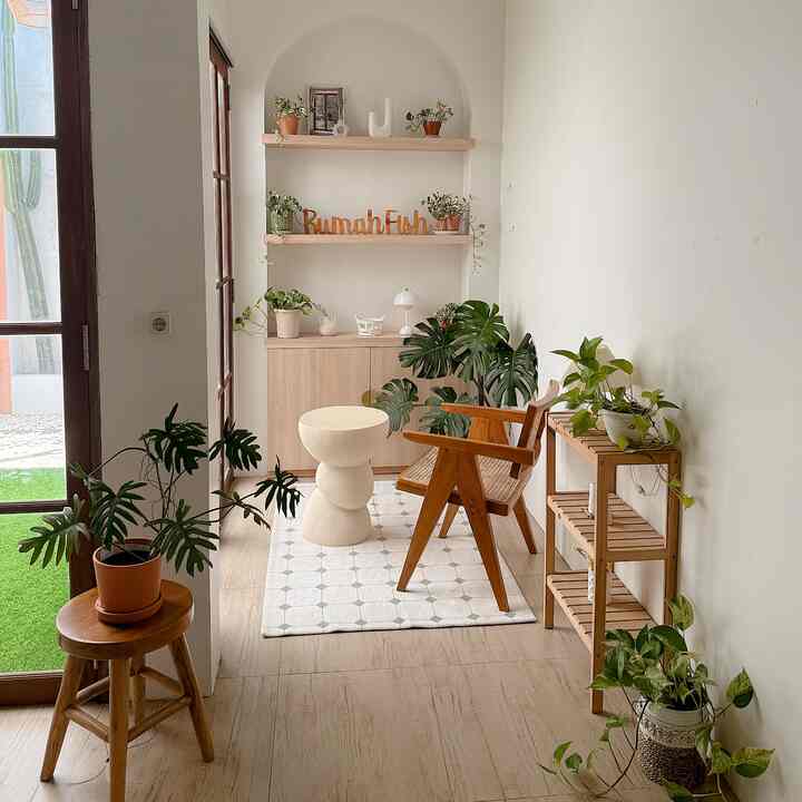 Bright wood tones and white walls in a narrow living room, featuring wooden chair and plant shelves in a natural modern space
