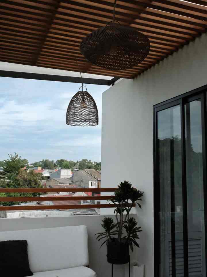 White walls and brown wood-tone balcony featuring a simple sofa and plant with a calm atmosphere