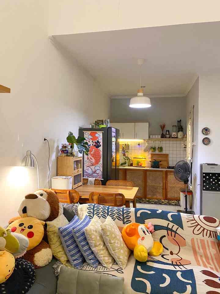 Natural wood tones and white colors blend in a cozy living and kitchen space featuring a sofa and dining table