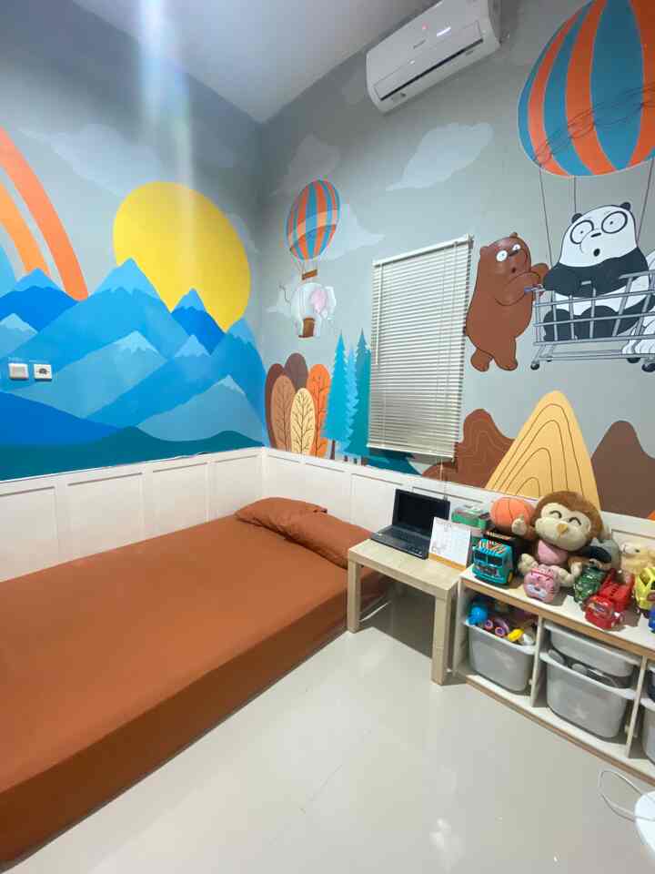 Kids' room with bright blue and yellow mural, featuring low bed and organized toy storage creating a cozy atmosphere