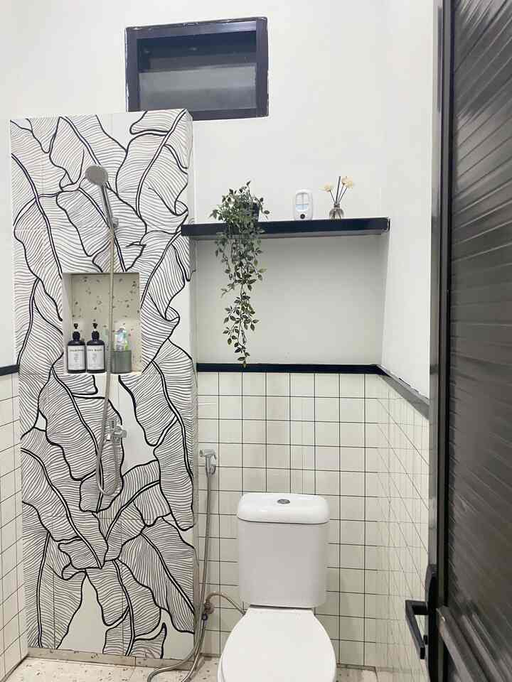 White and black toned bathroom featuring toilet and shower area with a clean and modern design