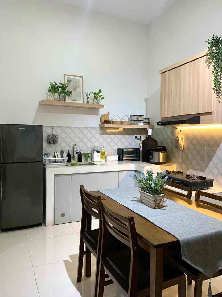 Bismillah,
Halo Tetangga Online,
aku Nadia @rumah.hma

Kali ini aku akan cerita sedikit tentang dapur minimalisku. Dapur di rumahku terletak di bagian sudut belakang berbentuk L. Desainnya simpel minimalis dan low budget 😬. Terdapat kabinet bawah warna abu-abu terang untuk menyimpan barang pecah belah dan peralatan memasak, kabinet atas dengan warna wood yg lembut untuk menyimpan stok makanan. Kupilih warna abu dan wood supaya dapurku keliatan terang dan ringkas. 

Fokal point di dapurku terletak pada 2 ambalan yg dipasang sengaja bersisian dan tidak sama tinggi. Aku sangat suka dengan figura yg kutambahkan di bagian atasnya. Untuk ambalan yang lebih rendah kumanfaatkan untuk menyimpan bumbu dapur dan bahan masak yang tidak disarankan disimpan di kulkas seperti bawang dan kentang.

Untuk rak pengering piring, tempat sendok, tempat tisu dll sebisa mungkin kupilih warna putih supaya clean dan simpel. Terakhir kutambahkan tanaman artifisial dan juga tanaman hidup supaya suasana terasa lebih alami.

#kitchenstyling #kitchendecorideas #kitchenmakeover #dapurminimalis #dapursimple #kitchensetminimalis