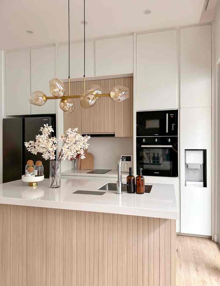 Modern kitchen in white and wood tones featuring black appliances and amber pendant lighting creating a sophisticated atmosphere