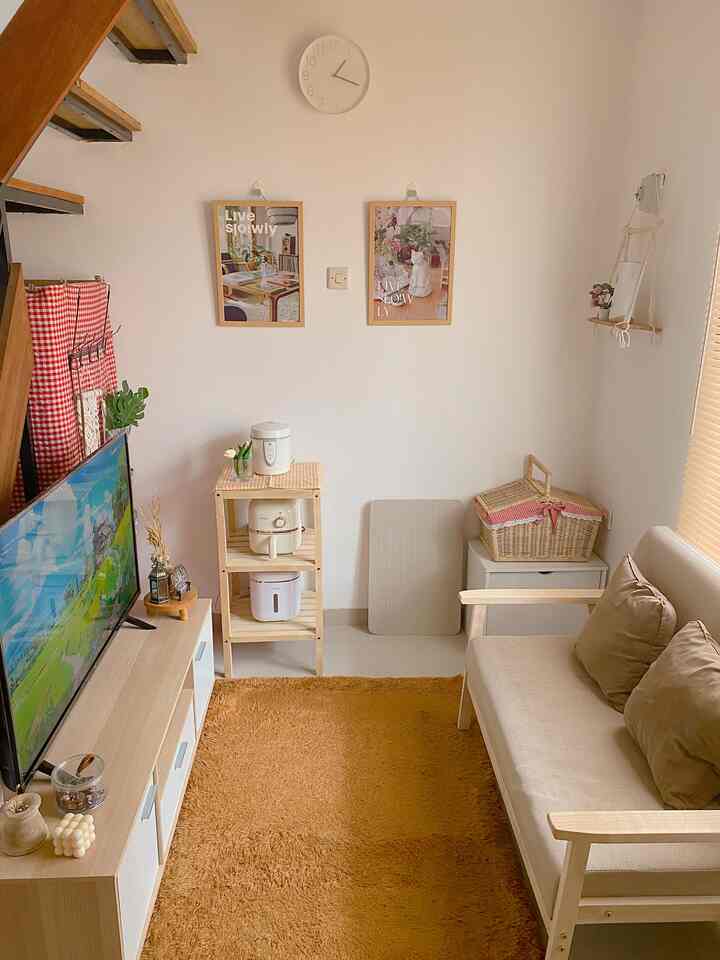 A cozy living room with white walls and wood tone furniture, featuring a beige sofa and mustard rug creating a warm atmosphere