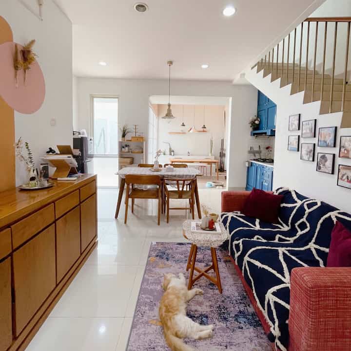 Modern living and dining room featuring navy and red sofa with wood-tone dining set and decor accents