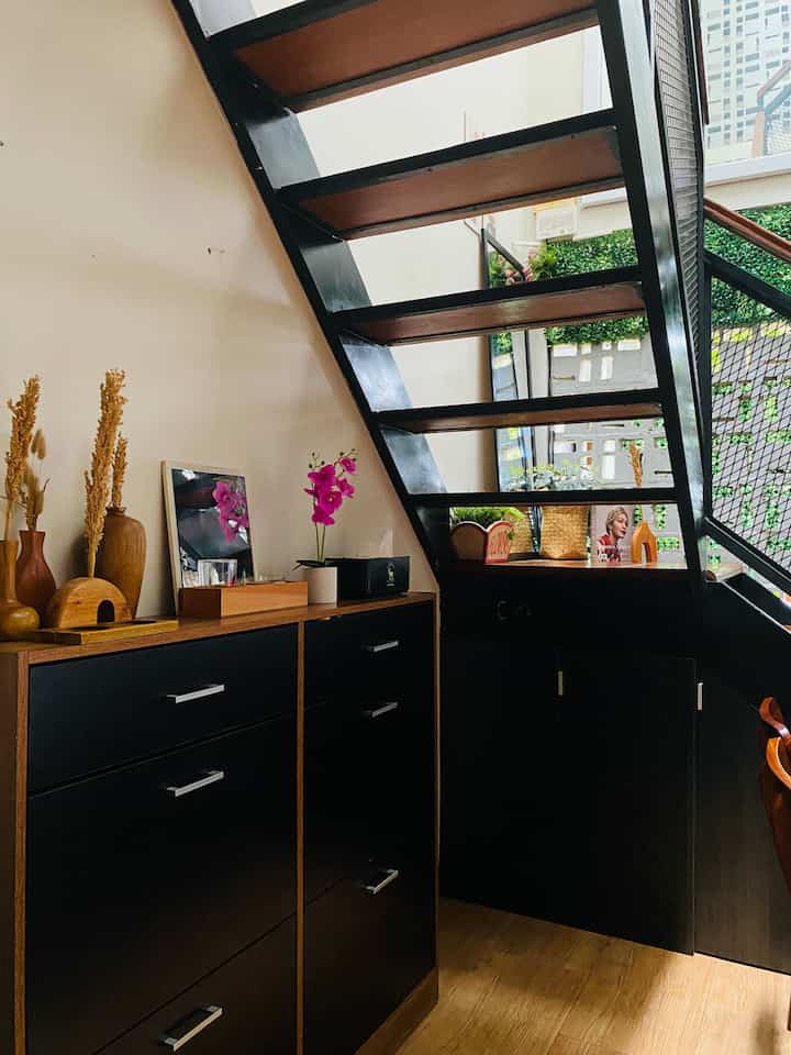 Cozy and stylish interior featuring a black and wood-toned shoe cabinet and modern staircase