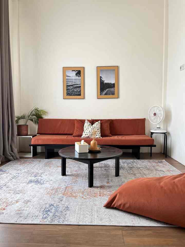Natural living room with white walls and brown floor, featuring orange sofa and bean bag
