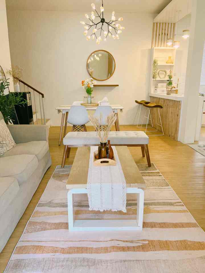 Natural wood tones and white hues blend in a compact dining and living room featuring a table runner and unique lighting