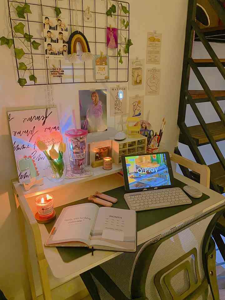 Cozy home office with warm lighting and pastel tones, featuring a white natural desk and colorful wall decor in a compact workspace