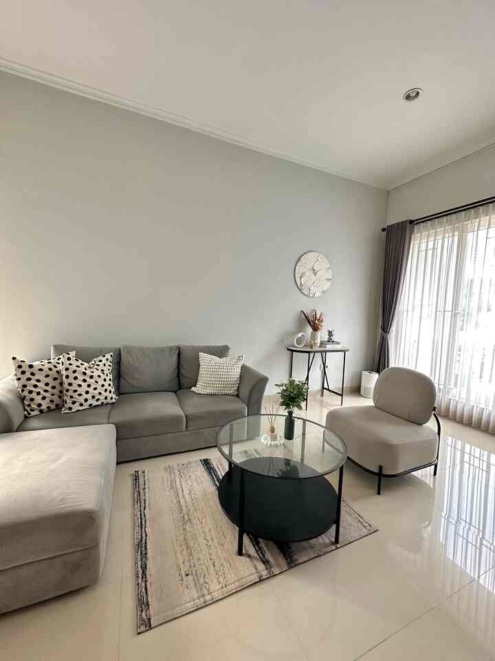 Bright beige and gray toned living room featuring a gray sofa, beige armchair, and round glass coffee table with a clean natural vibe
