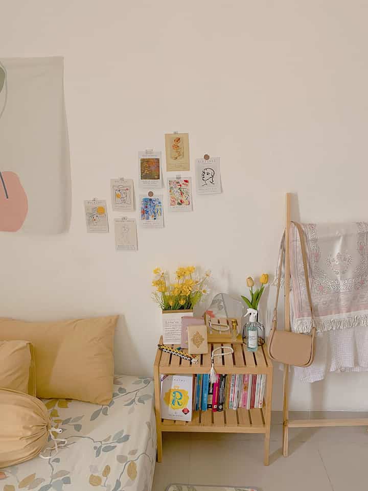 Cozy living room in soft natural tones featuring flower vases, wooden shelves, and art posters displayed on the wall