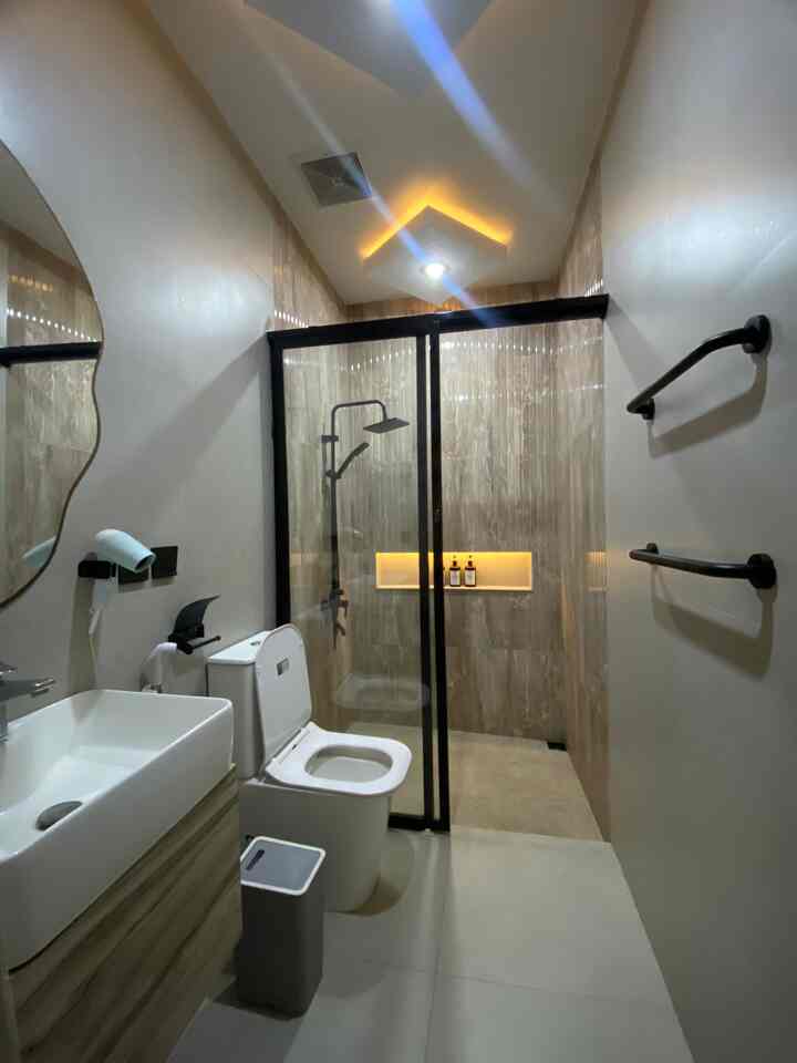 Modern bathroom featuring brown tiled shower area and white fixtures, separated wet and dry zones with clean interior design