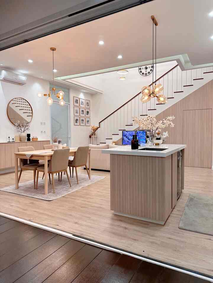 Wood tone and ivory open plan dining room and kitchen with pendant lighting and plant decorations in a modern setting