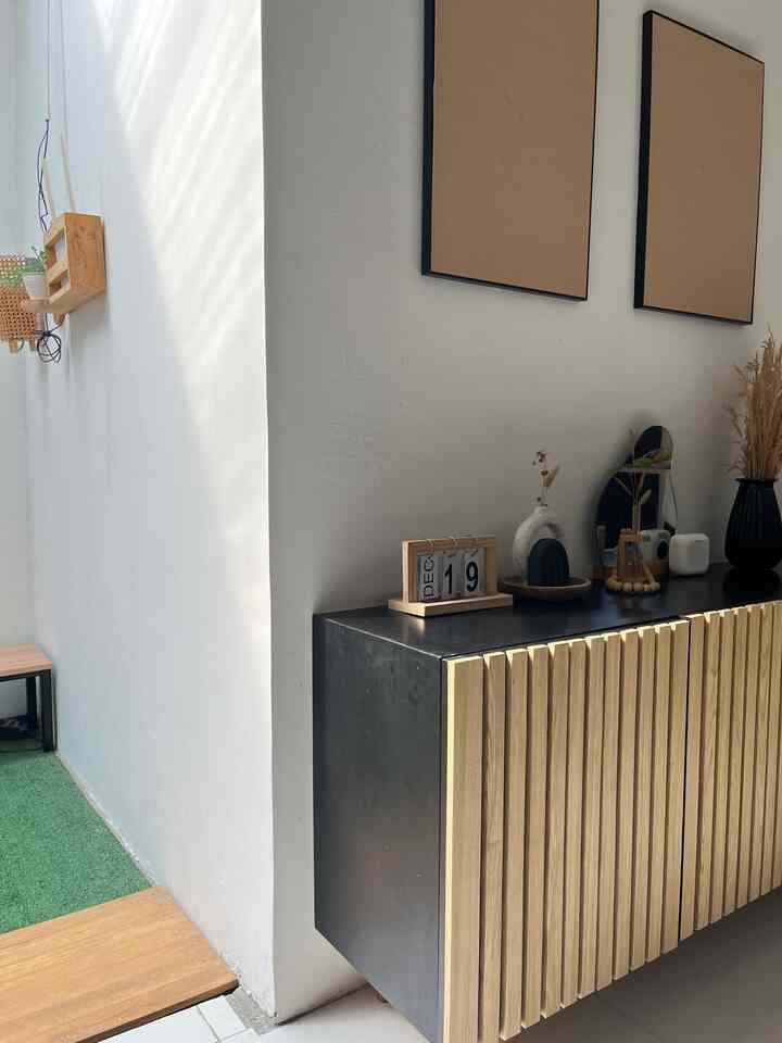 A clean entrance space with white walls and natural wood tone storage cabinet, featuring minimal decor and natural light