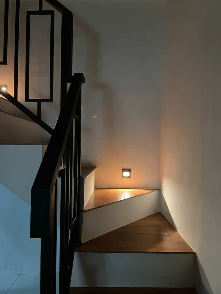 Inilah salah satu night vibe favoritku dirumah.
Sedikit bercerita tentang anak tangga, awalnya di design dengan  keramik biasa berwarna putih namun akhirnya saya memutuskan untuk menggantinya dengan motif kayu yang bertujuan agar area tangga memiliki unsur aesthetic. 
Alhamdulillah puas dengan hasilnya dan menurutku hal tersebut merupakan pilihan yang tepat. 
Pemilihan railing tangga berwarna hitam dengan pola minimalis modern diselaraskan dengan anak tangga, tidak lupa juga kami lengkapi dengan pemasangan lampu sorot yang berfungsi selain untuk penerangan juga meningkatkan nilai aesthetic dirumah mungil ini. 

#nightvibes
#lightingideas
#lightinginspiration
#stairs
#inspirasitanggaminimalis
#designrailingtangga

