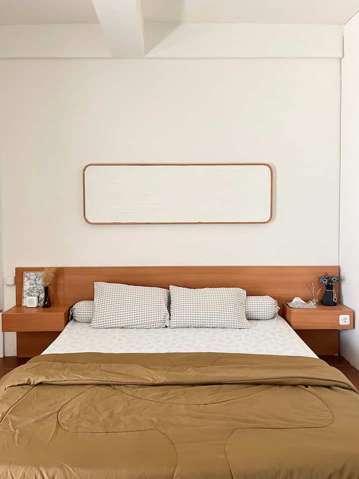 Beige and wood tone bedroom featuring a low-profile bed and simple wall art, creating a cozy and natural atmosphere