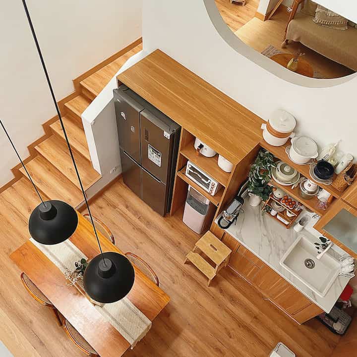 Bright wood-tone floor and dining table in white-toned kitchen and dining room, featuring pendant lights for a warm atmosphere
