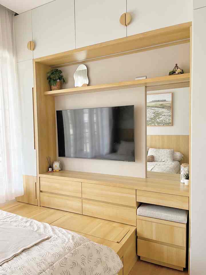 Beige and wood tone bedroom featuring a TV mounted above wooden storage with a clean and natural atmosphere