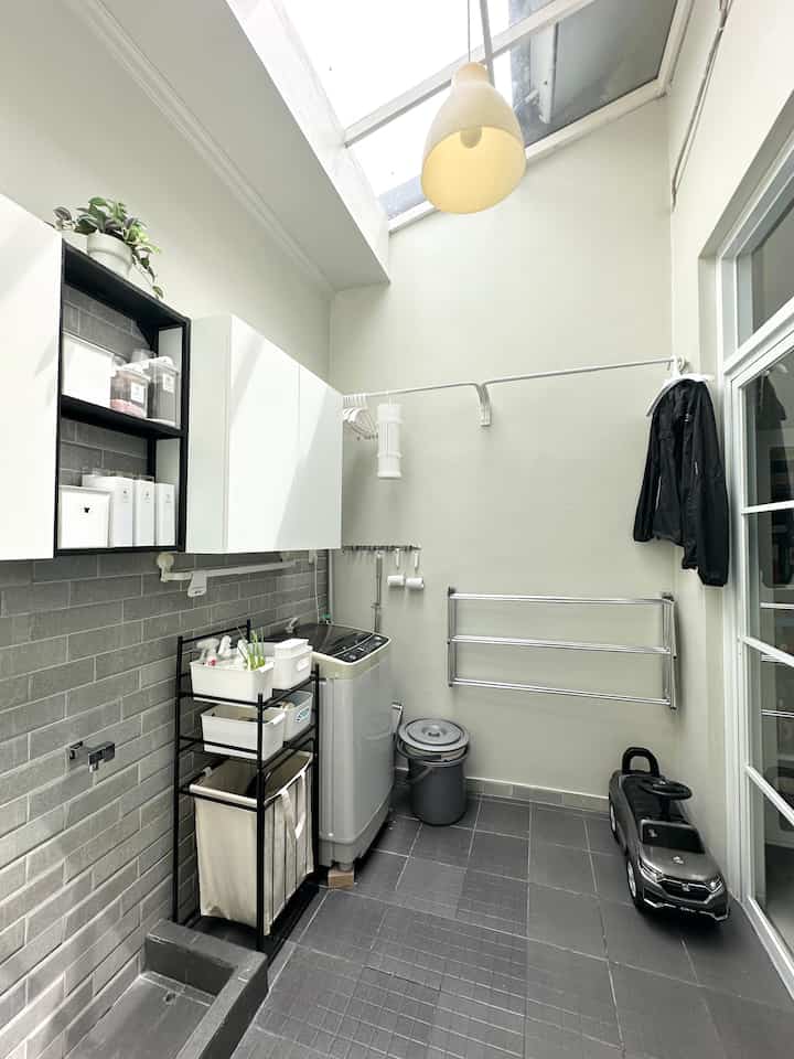 White and gray toned small laundry room featuring washing machine, storage cabinets, and a skylight providing bright atmosphere