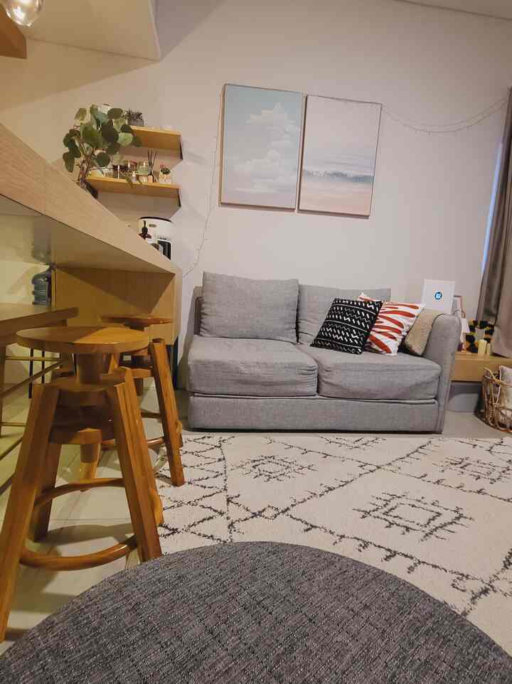 Beige-toned compact living room kitchen featuring gray sofa and wooden stools with warm atmosphere