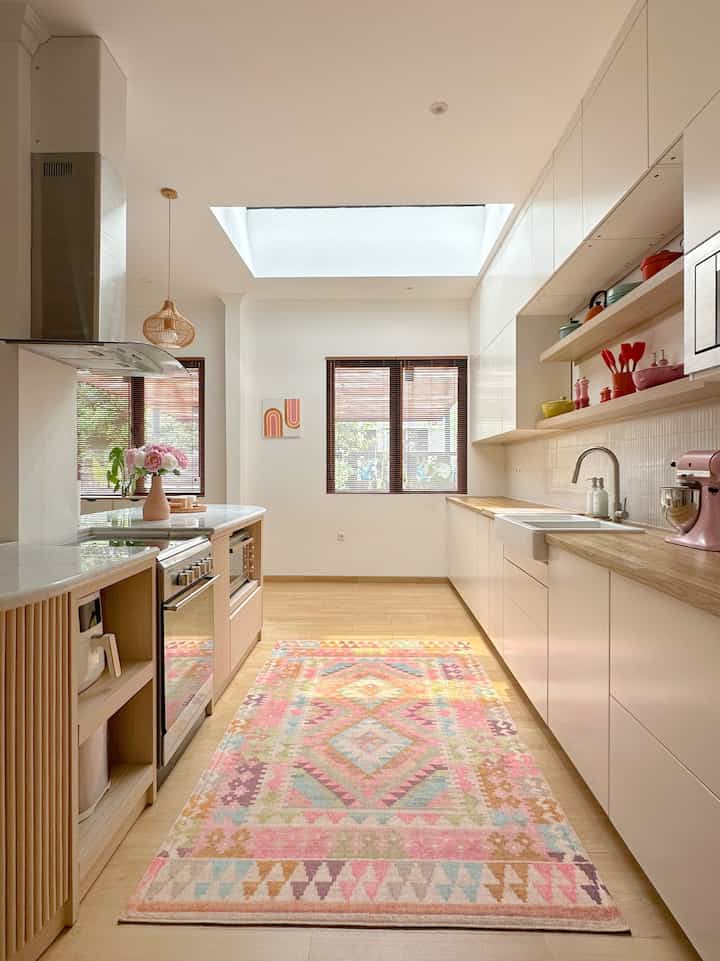 White and wood tone kitchen space featuring a bohemian style carpet with natural lighting creating a clean and cozy atmosphere