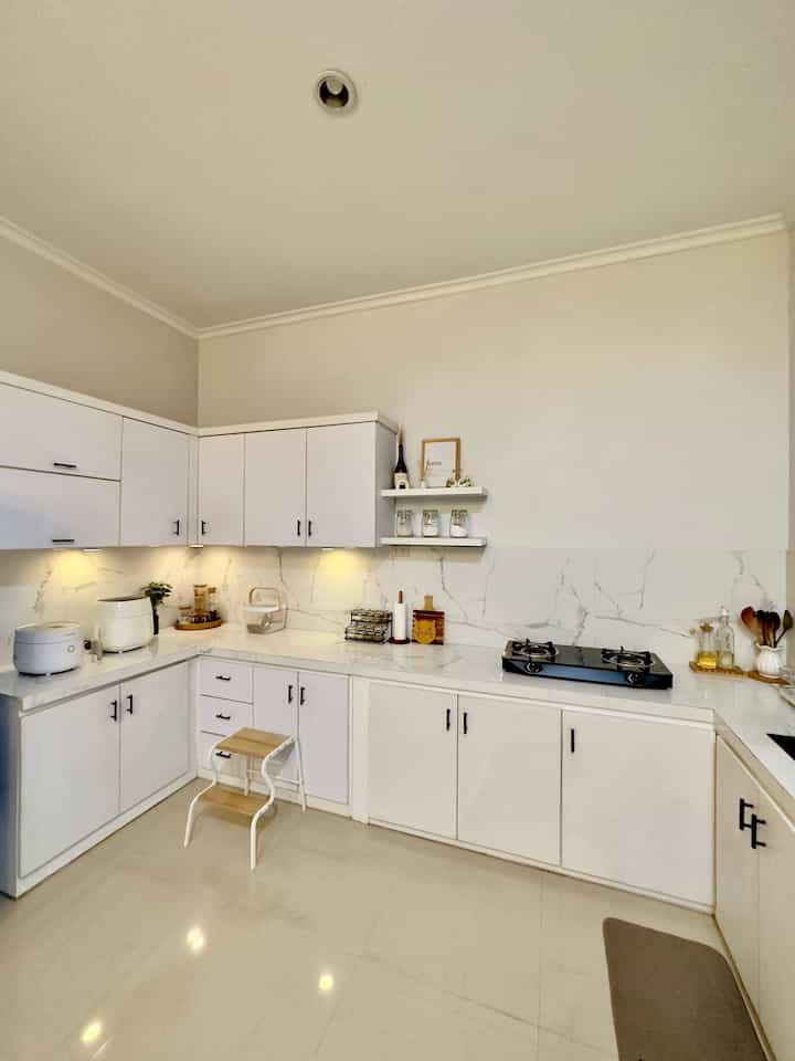 White-toned kitchen space featuring clean cabinetry and furniture arranged in a simple interior design