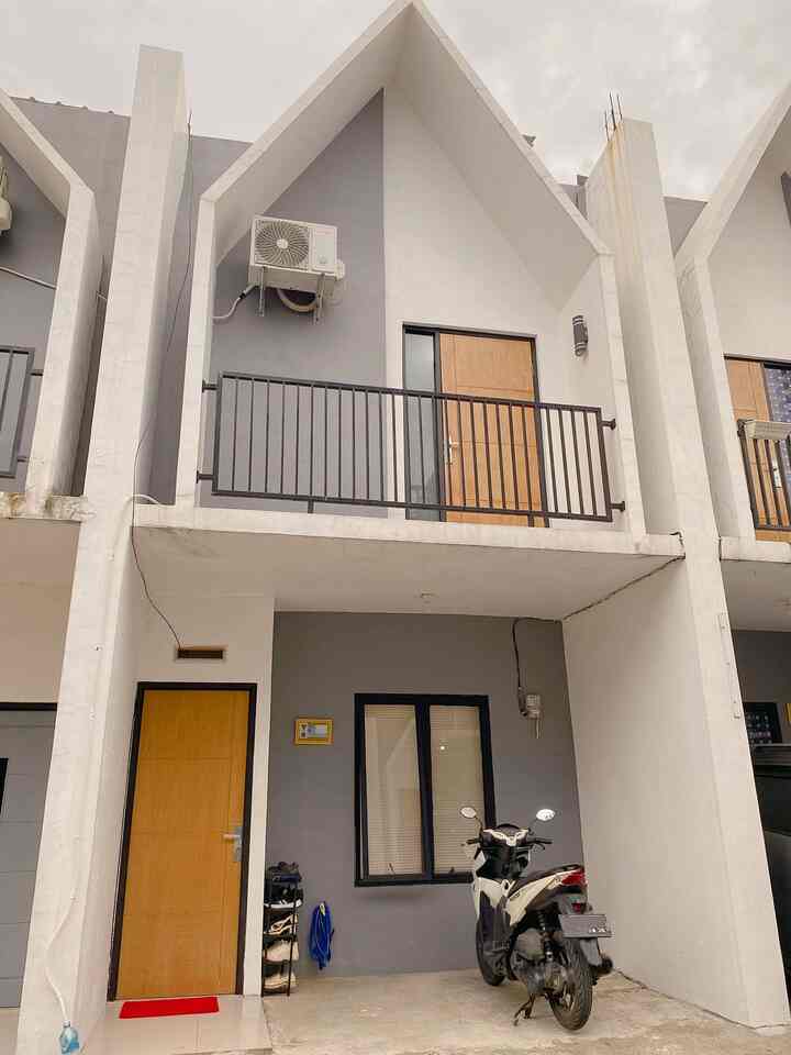 Modern two-story house facade in white and gray tones featuring wood-tone entrance door and balcony with a clean exterior