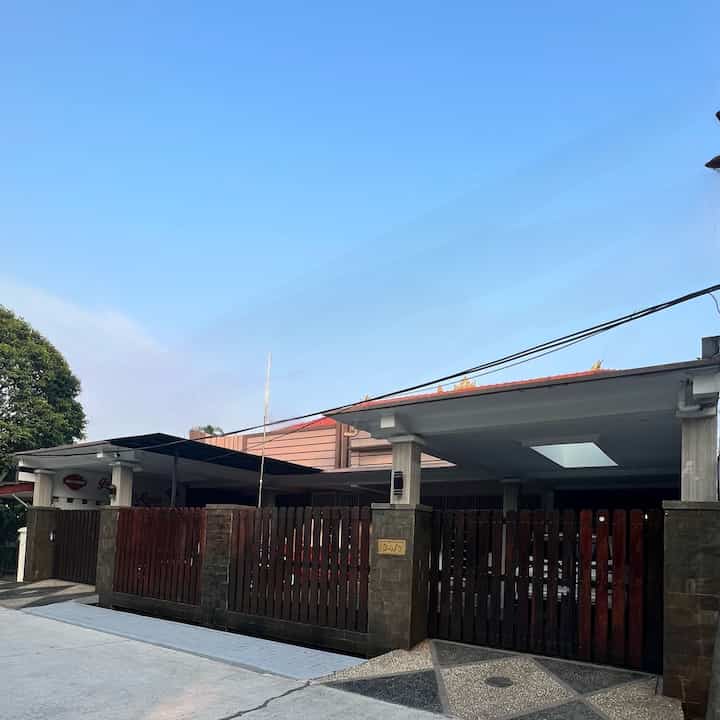 Minimal style house facade featuring wood tones and stone finishes with an entrance and fence under clear blue sky