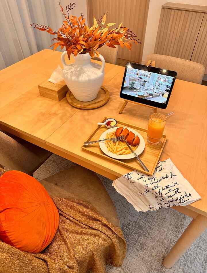 Beige-toned dining room featuring wooden table with white vase and orange cushion creating cozy atmosphere