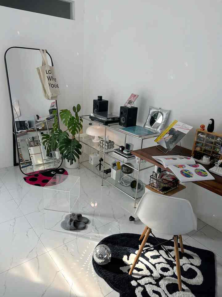 White and simple modern tone home office featuring a desk, office chair, chrome shelving, and large mirror in a clean interior