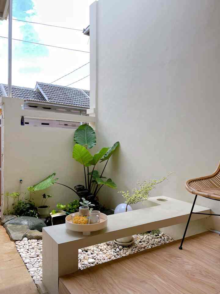A white and beige toned balcony featuring wood tone chair and various plants creating a serene resting space