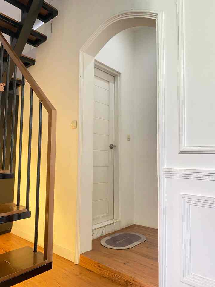 White-toned compact bathroom entrance with wooden stairs and railings on the left side