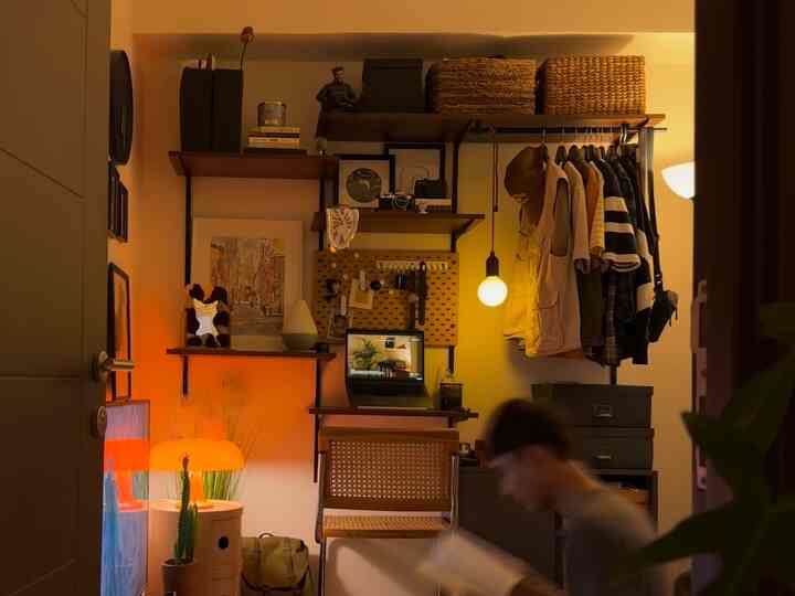 Warm brown and yellow toned compact studio home office featuring desk, shelves, and pendant lighting creating cozy atmosphere