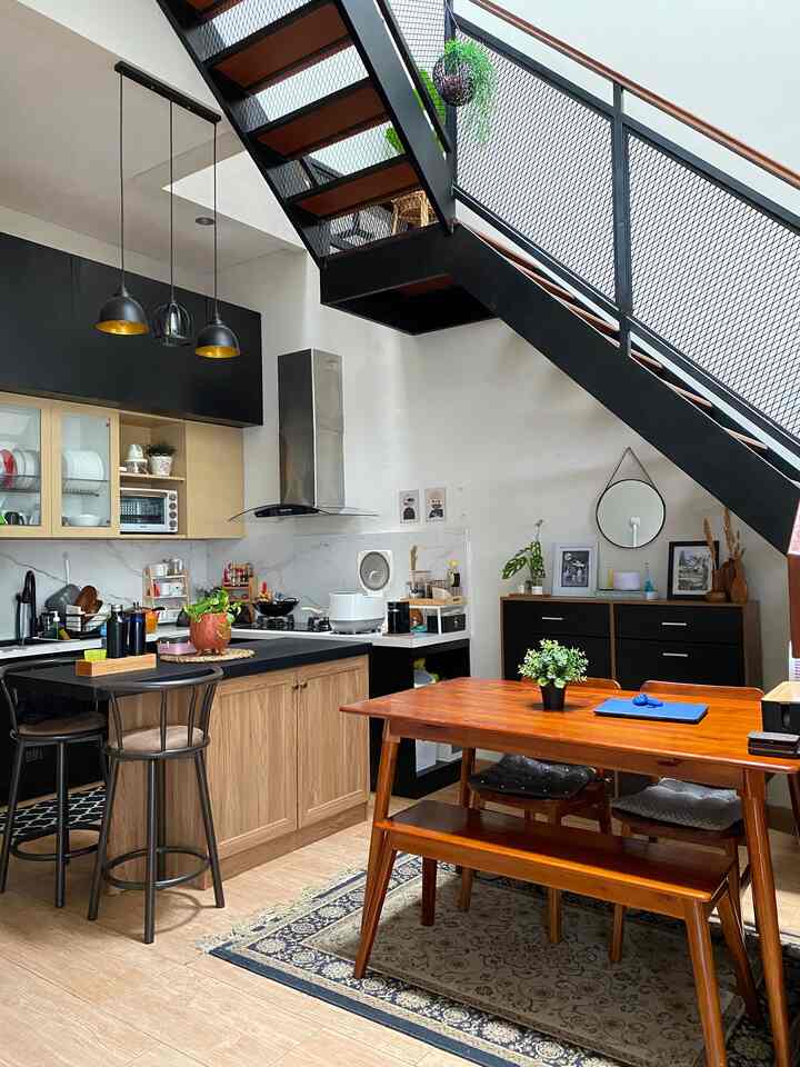 Wood tone and black themed kitchen and dining room with staircase layout, showcasing a blend of industrial and Scandinavian interior styles