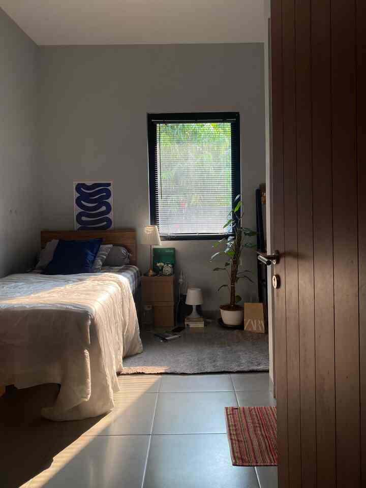 Gray-walled small bedroom with tiled floor, featuring navy cushion and white bedding in Mid-Century Modern style