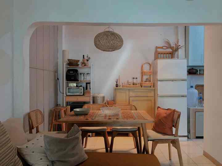 Beige and wood tone kitchen space featuring wooden dining table and chairs with a rattan pendant light creating a cozy atmosphere