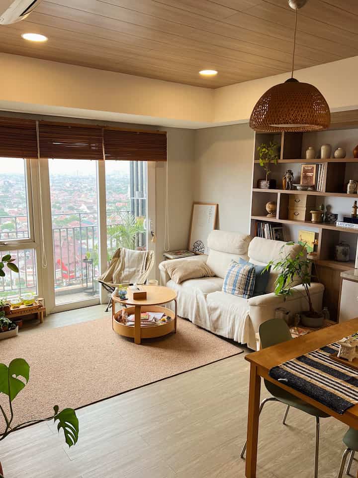 Natural wood tone and white living room featuring sofa, round coffee table, and dining table arranged comfortably