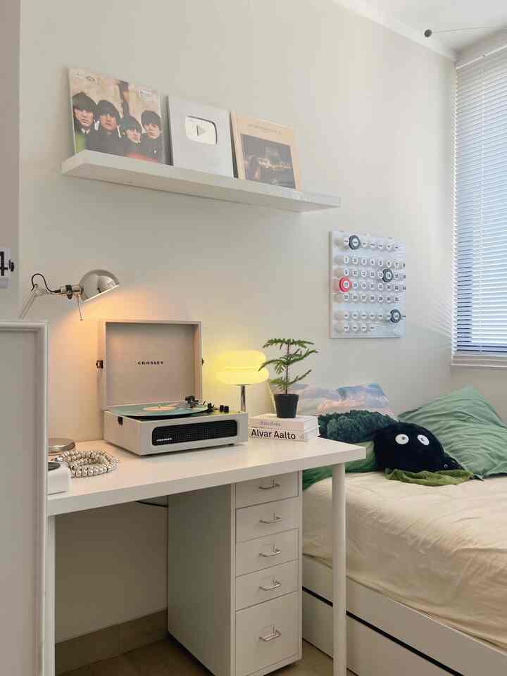 White and green toned bedroom featuring a desk and table lamp with a clean, minimal atmosphere