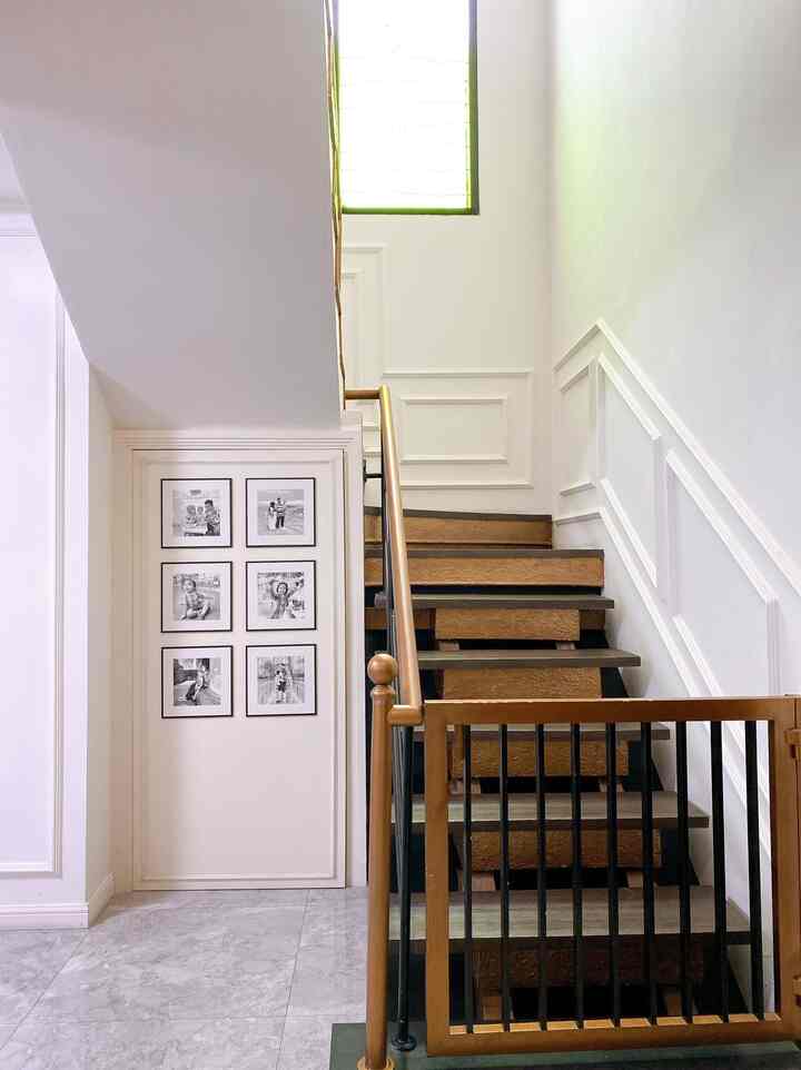 Narrow stairwell with white walls and brown handrail, featuring a pet safety gate at the bottom and clean, minimal decor