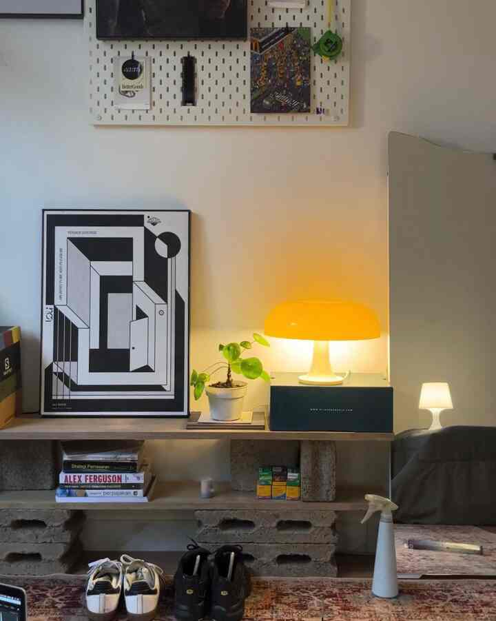 White-wall entrance area featuring yellow table lamp, plant, and poster creating a cozy atmosphere