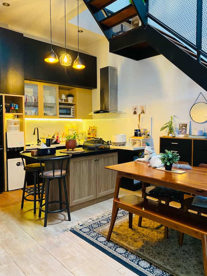 Natural living-kitchen loft apartment featuring wood-tone dining table, warm pendant lights, and cozy decor