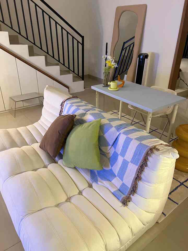 White and blue toned living room featuring a Togo sofa with checkered throw blanket in a minimal and comfortable space