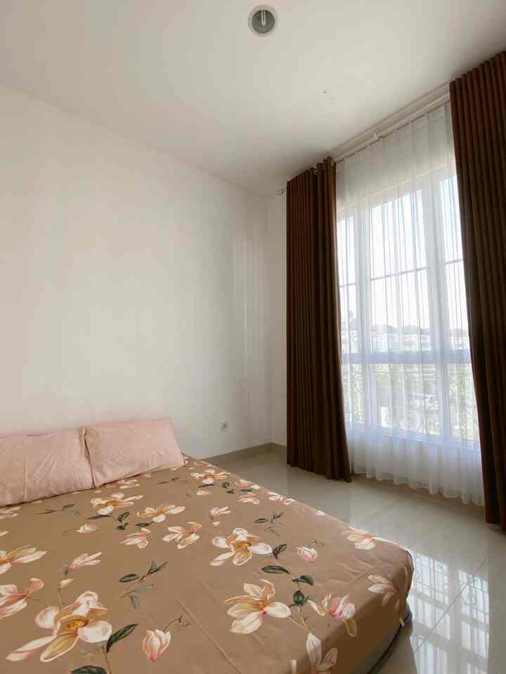 Bright and clean bedroom with beige floral bedding and brown curtains