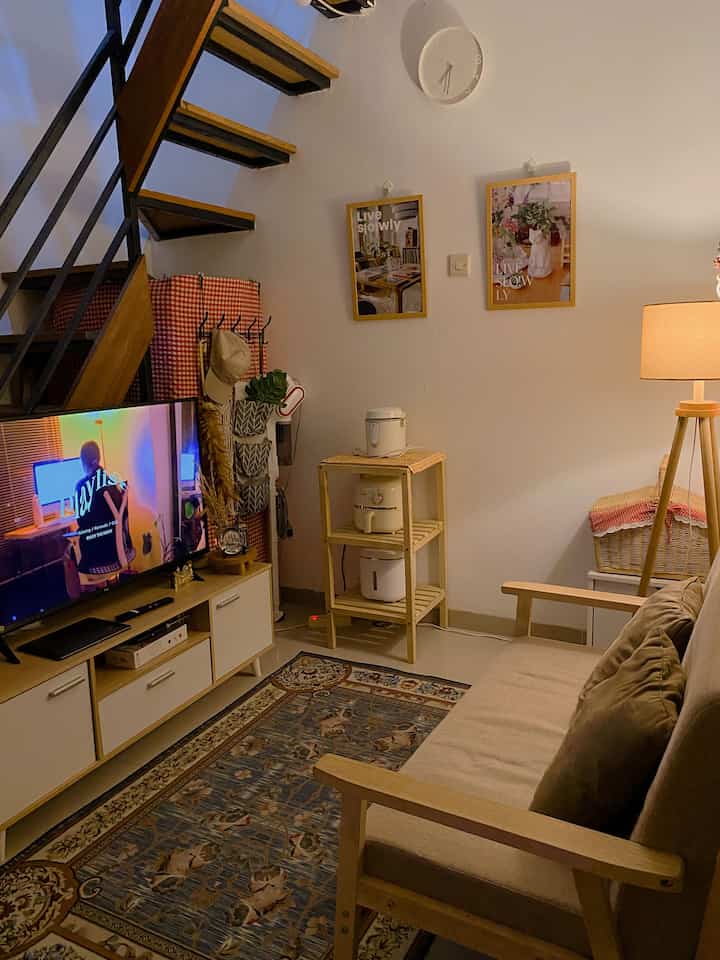 Natural wood tones and white-walled living room featuring a sofa and TV stand arranged cozily