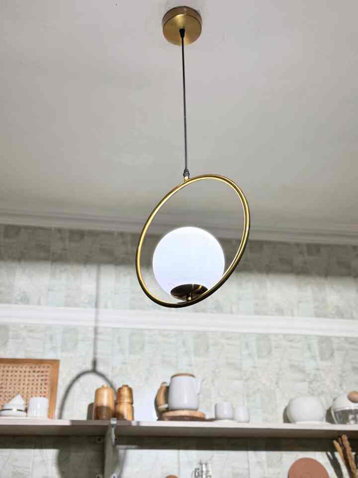 Modern kitchen space with a pendant light featuring a gold ring and white glass globe