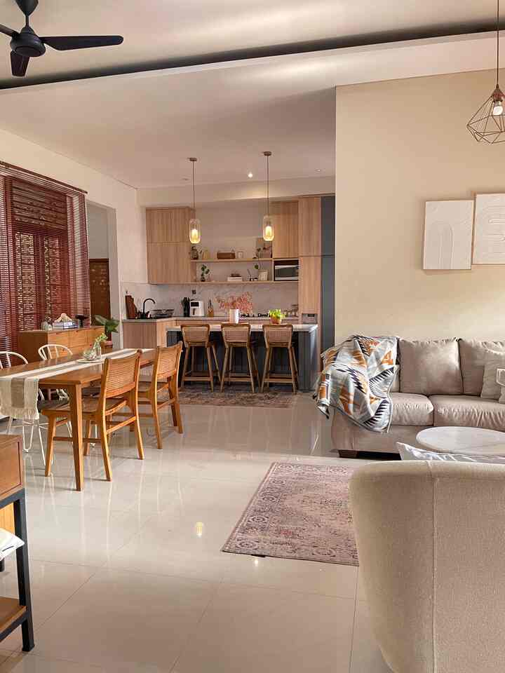 Warm wood tones and white walls in living and dining area featuring wooden dining table and beige sofa in a natural modern style