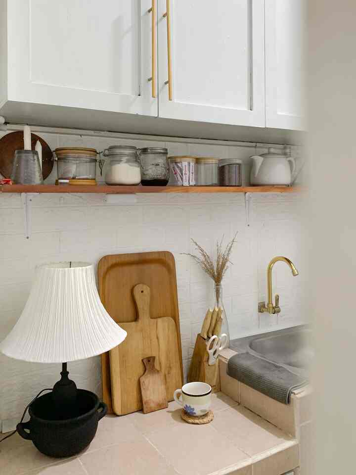 Compact kitchen in natural white tones featuring wooden cutting boards and kitchen essentials, creating a cozy atmosphere
